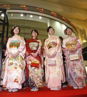 Chicas en kimono posando ante la pantalla de cotizaciones de la Bolsa de Tokio